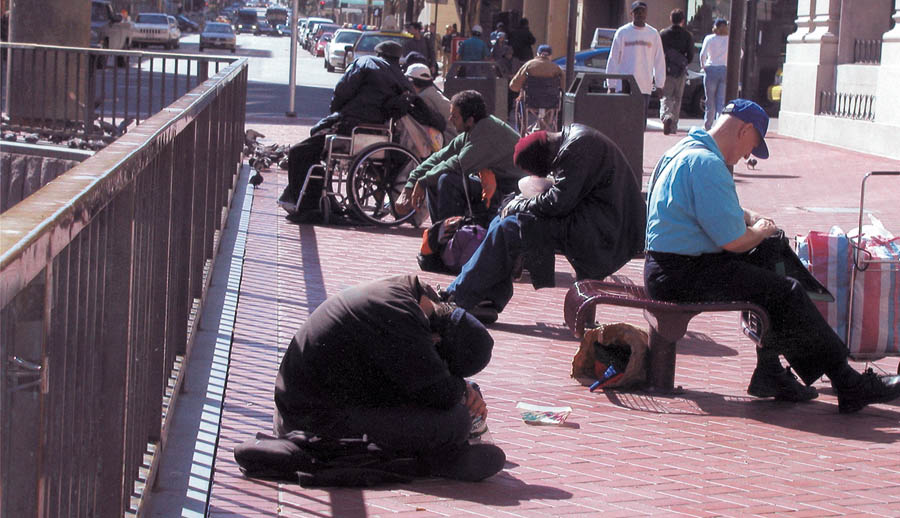 A row of homeless men sitting on a San Francisco sidewalk. Photo by Lydia Gans