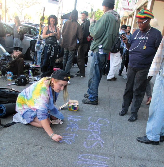 In defiance of Berkeley’s laws that criminalize homeless people for sleeping outdoors, a protester uses colored chalk to speak out against repression. Sarah Menefee photo