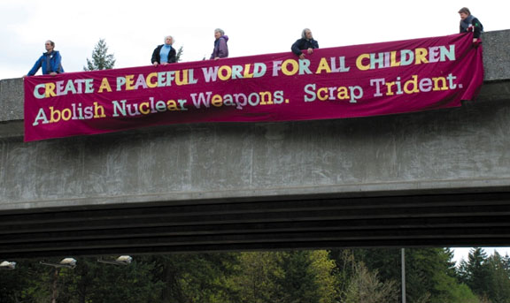 Trident protesters on a freeway overpass: “Create A Peaceful World For All Children. Abolish Nuclear Weapons. Scrap Trident.” Photo courtesy Ground Zero Center