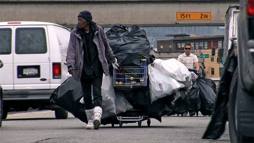 A recycler hauls a heavy load on the streets of West Oakland in this scene from Dogtown Redemption.