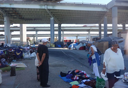 People bring breakfast to a homeless encampment in Oakland. Kwalin Kimaathi photo