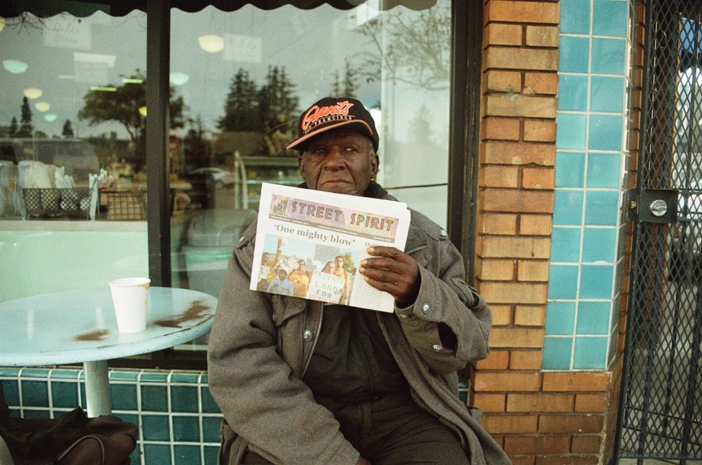 Art poses for a photo outside Sweet Adeline Bakeshop in Berkeley, where he used to sell Street Spirit.