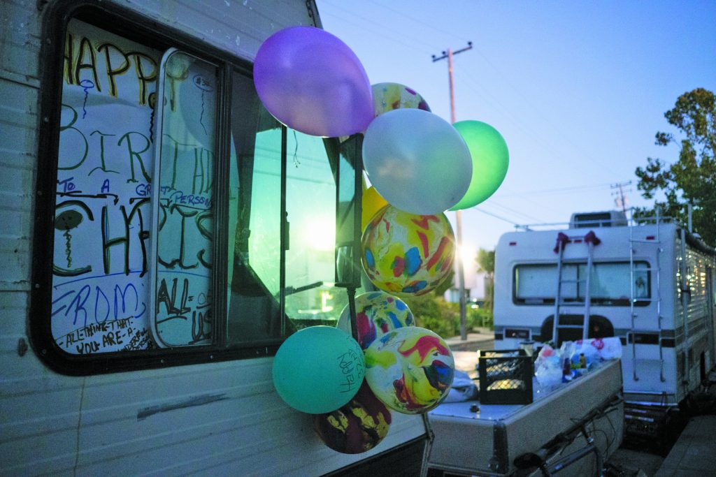 Balloons and birthday decorations hang on Chris Castle’s recreational vehicle on 8th and Harrison streets in the Gilman District. Neighbors celebrate Castle’s 29th birthday, cooking up in a barbecue and eating cake after the surrounding businesses have closed for the day.