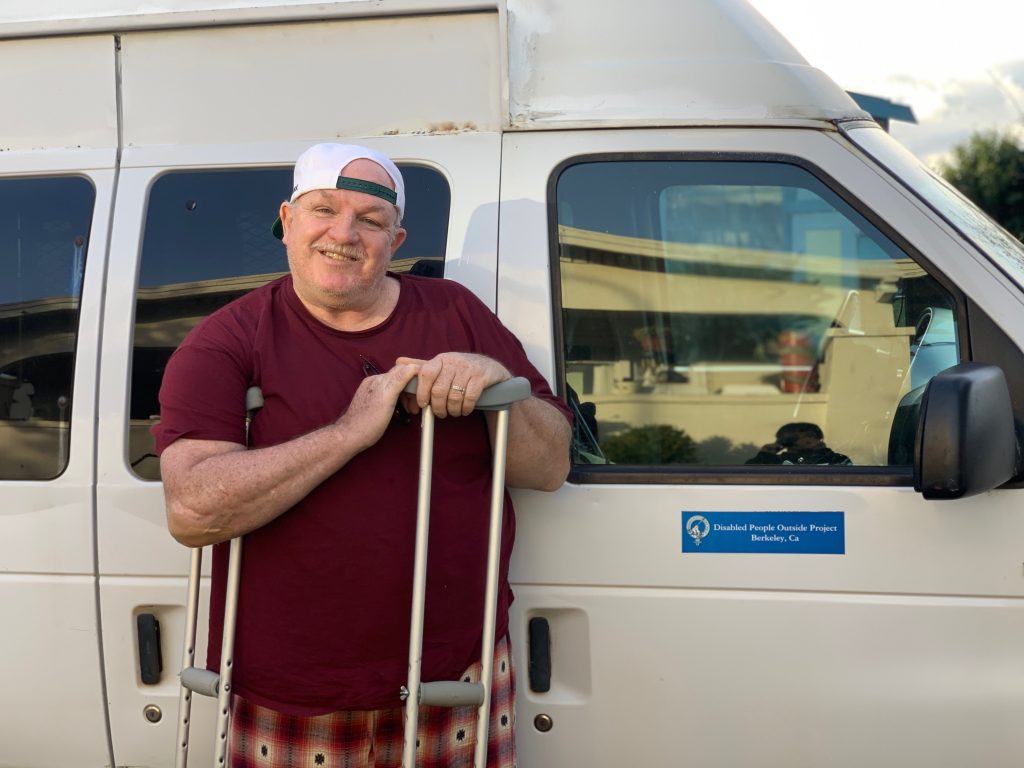 Danny McMullan stands with a Disabled People Outside Project van. 
