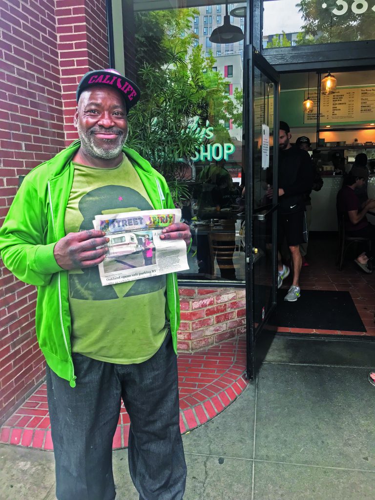 Hayes holds up a copy of Street Spirit outside Beauty's Bagels in Oakland.