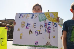A student from the Berkeley School holds a sign that reads, “Every bee needs a hive.