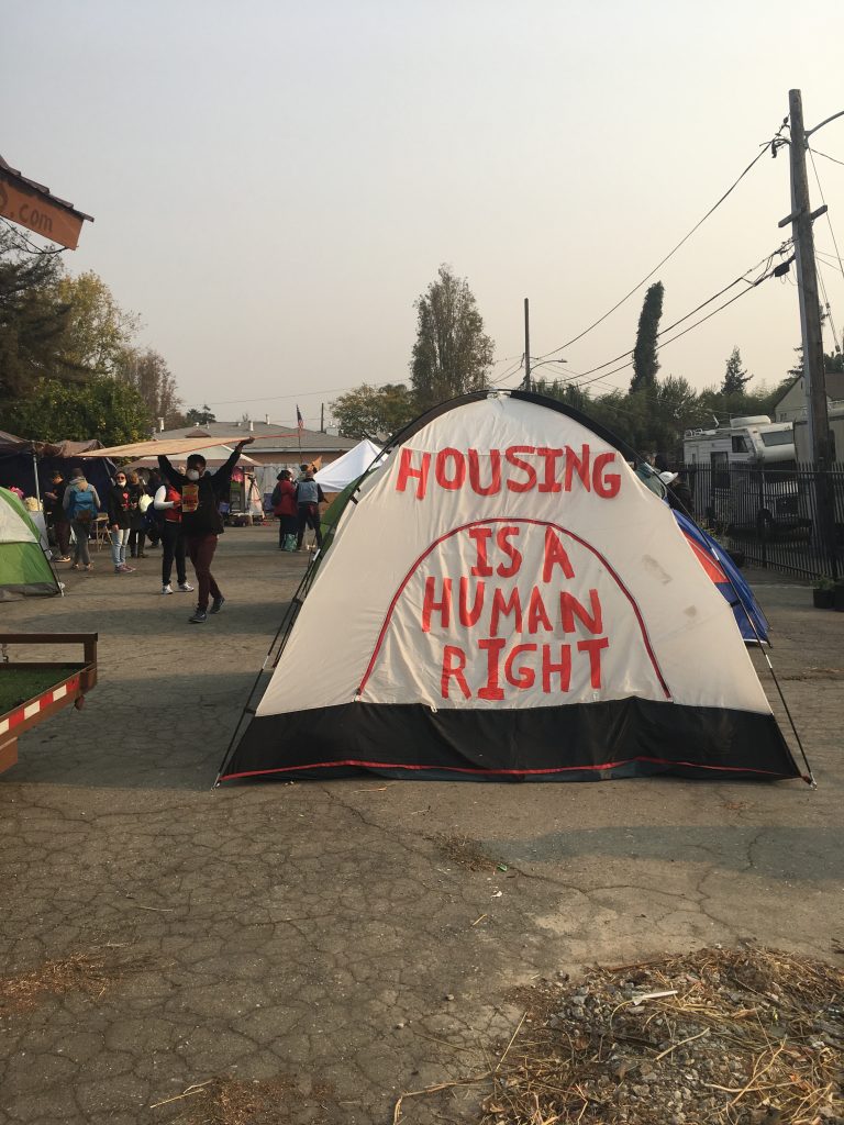 Text on the side of a tent reads "Housing is a human right."