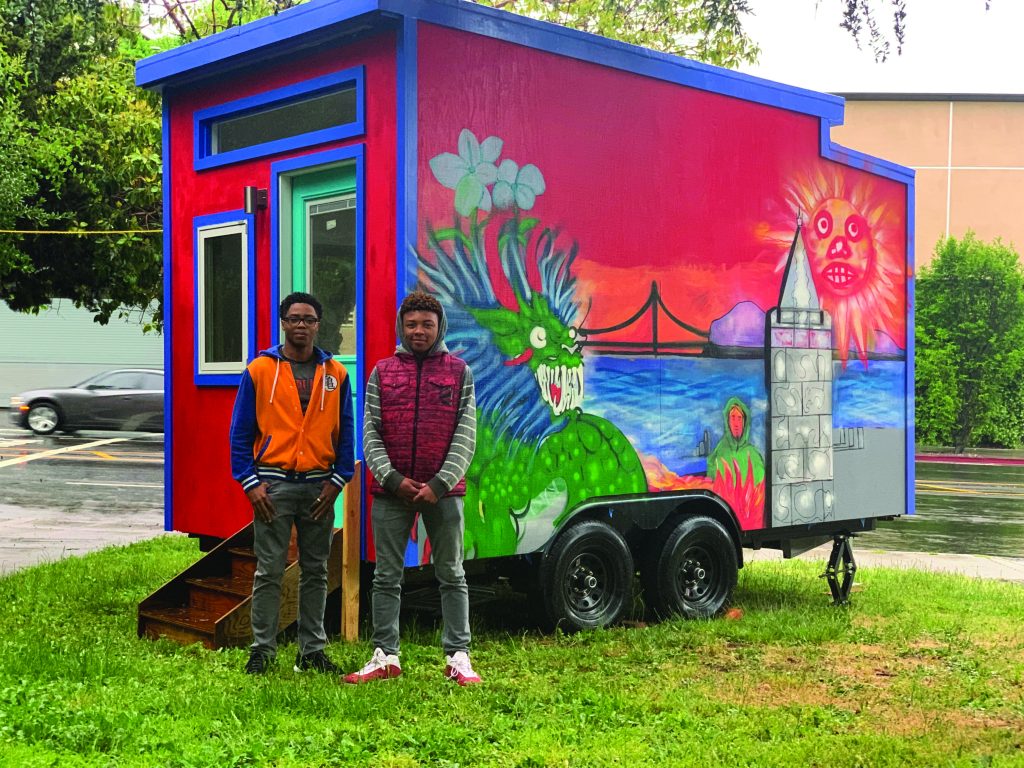 Youth Spirit Artworks leaders Jason Wilson and Zaire Caldwell (stand in front of a tiny home.