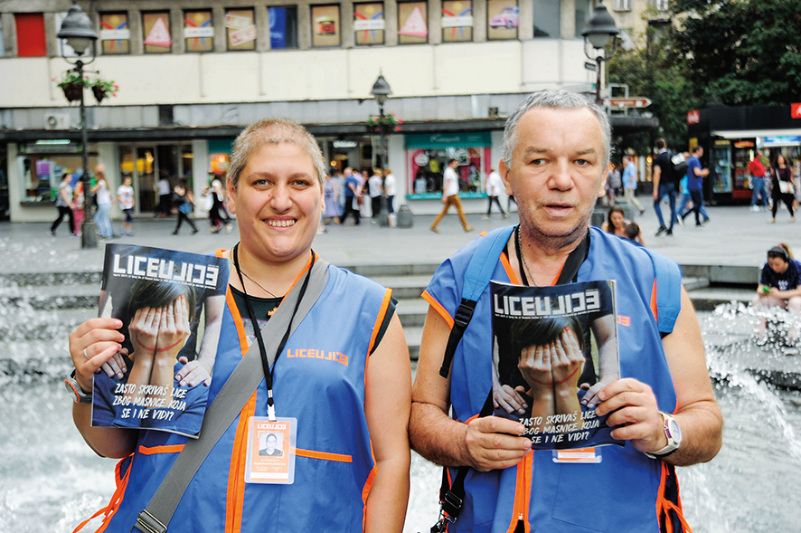 Bojana Ivanov Ljubomirov and Petar Jugovic pose for a photo while holding up copies of the magazine they sell, LiceuLice.