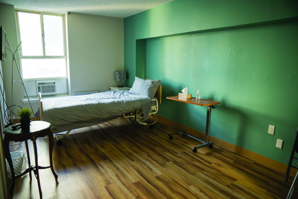 A hospital bed sits in a well lit room with light green walls.