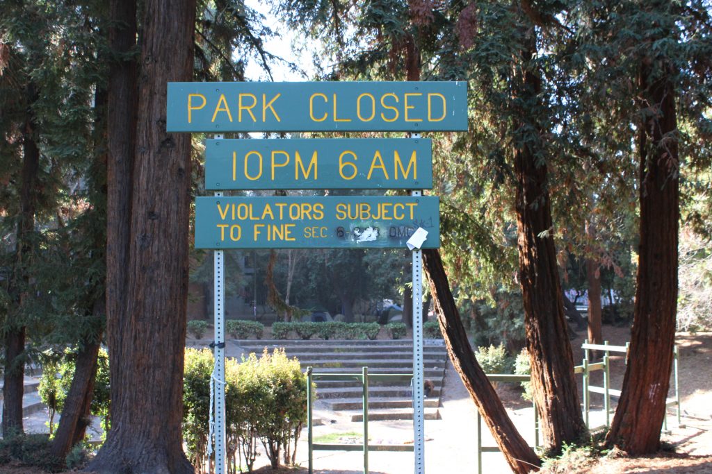 A sign at Oakland's Mosswood Park reads "park closed 10 pm - 6 am violators subject to fine"
