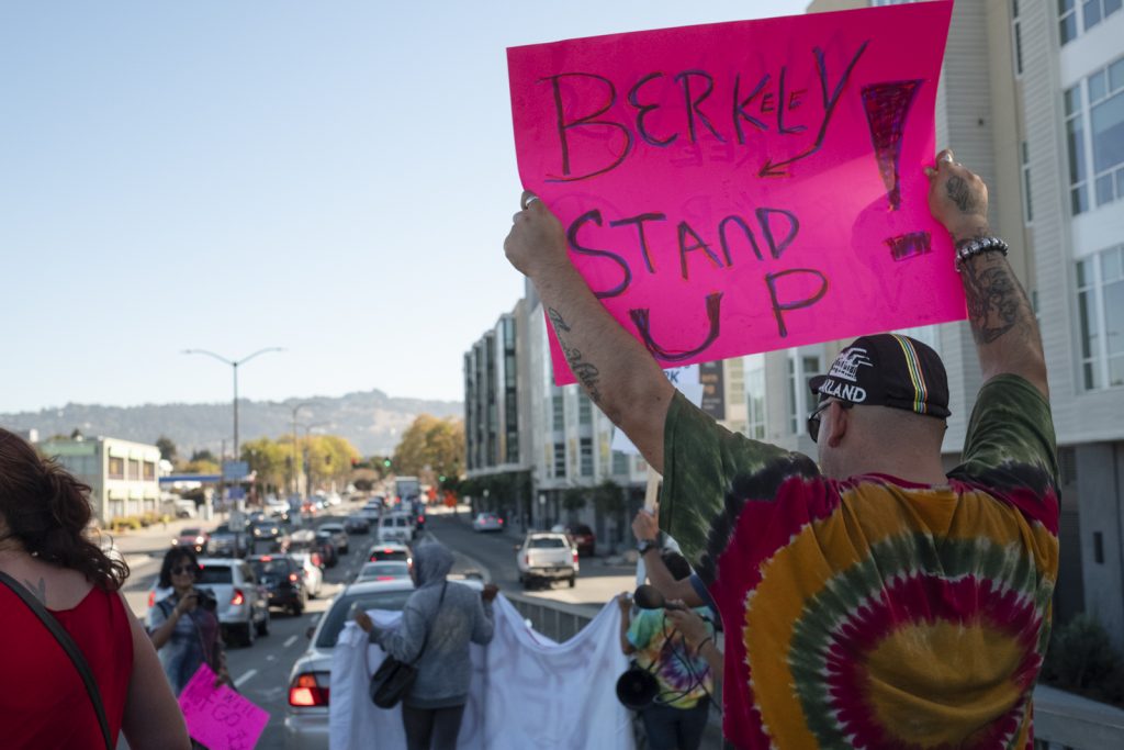 Protestors on University Ave. Man holds, "Berkeley Stand up!" sign. 
