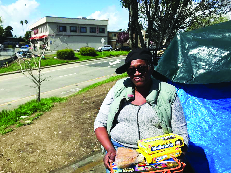 Cella Jones sits outside her tent with boxes of snacks. 