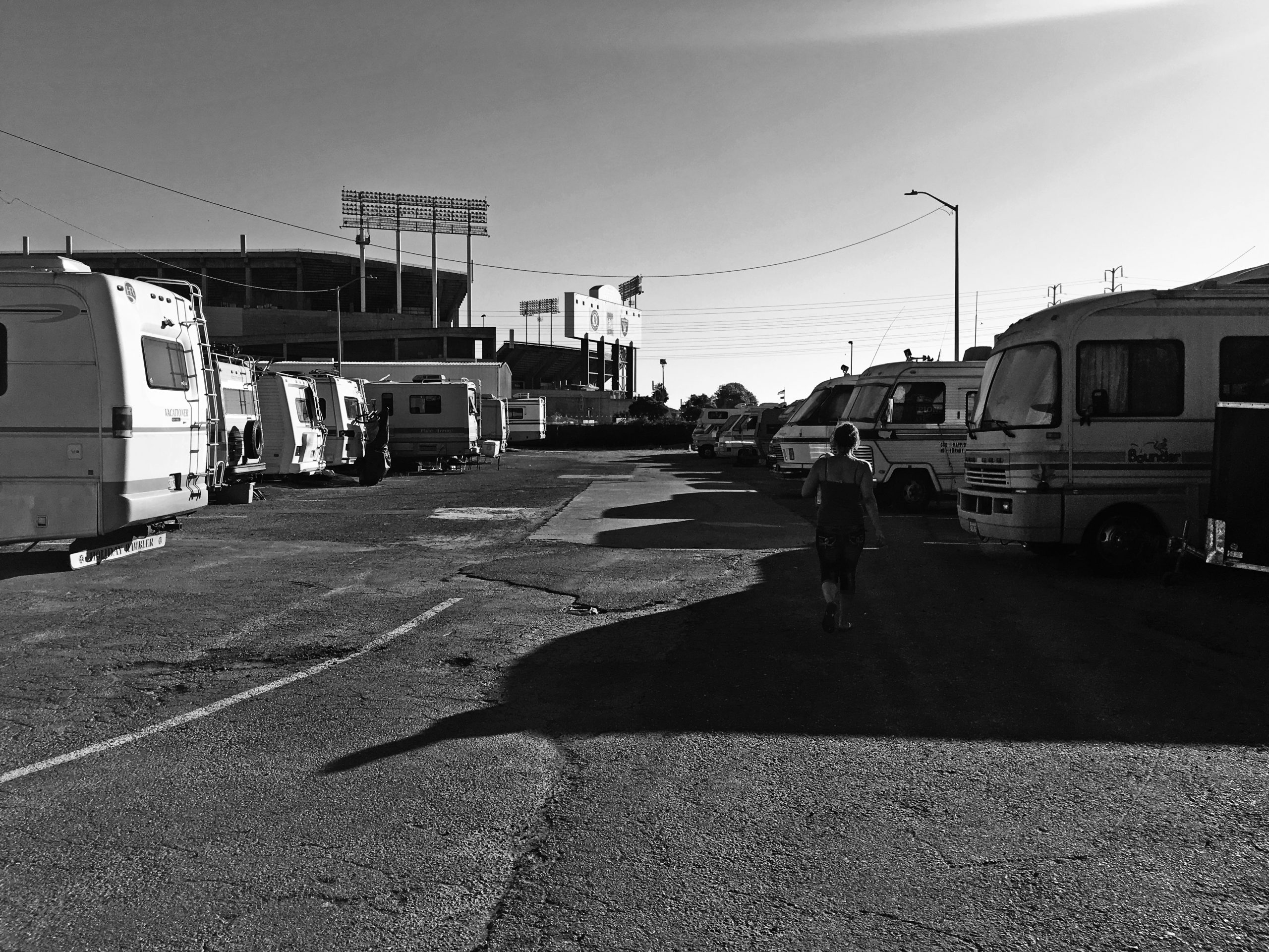 Black and white image of two rows of RVs. A solitary woman walks between them.