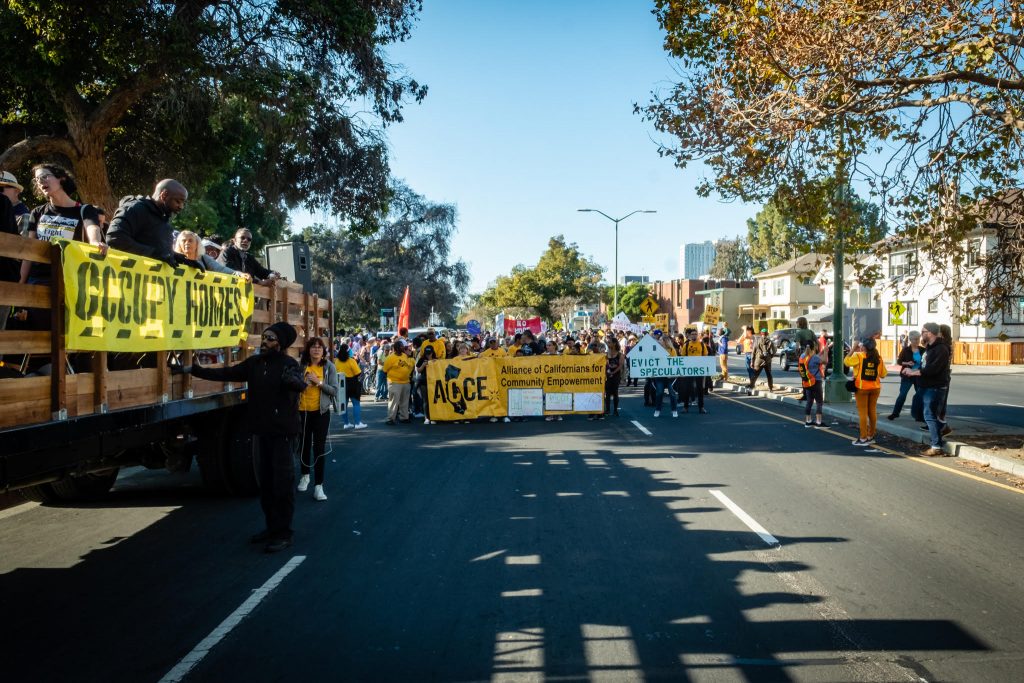 Photo of march. Alliance of Californians for Community Empowerment banner visible. 