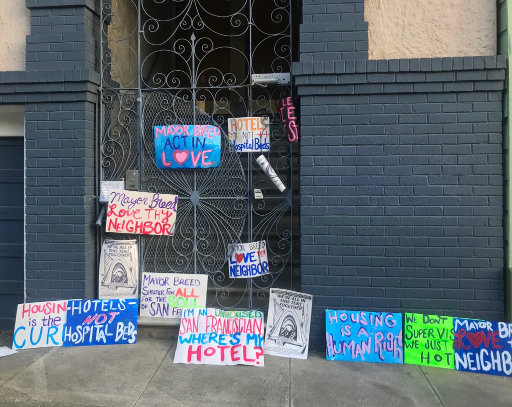 Colorful protest signs left on the mayor's doorstep. Messages read "mayor breed act in love", "mayor breed love thy neighbor," "I'm an unhoused San Franciscan where's my hotel?" as well as other messages.