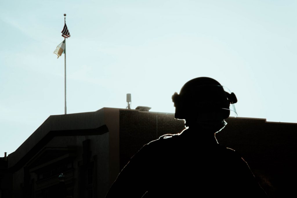 The silhouette of a police officer can be seen standing on San Francisco's 17th street. The sun shines behind them.