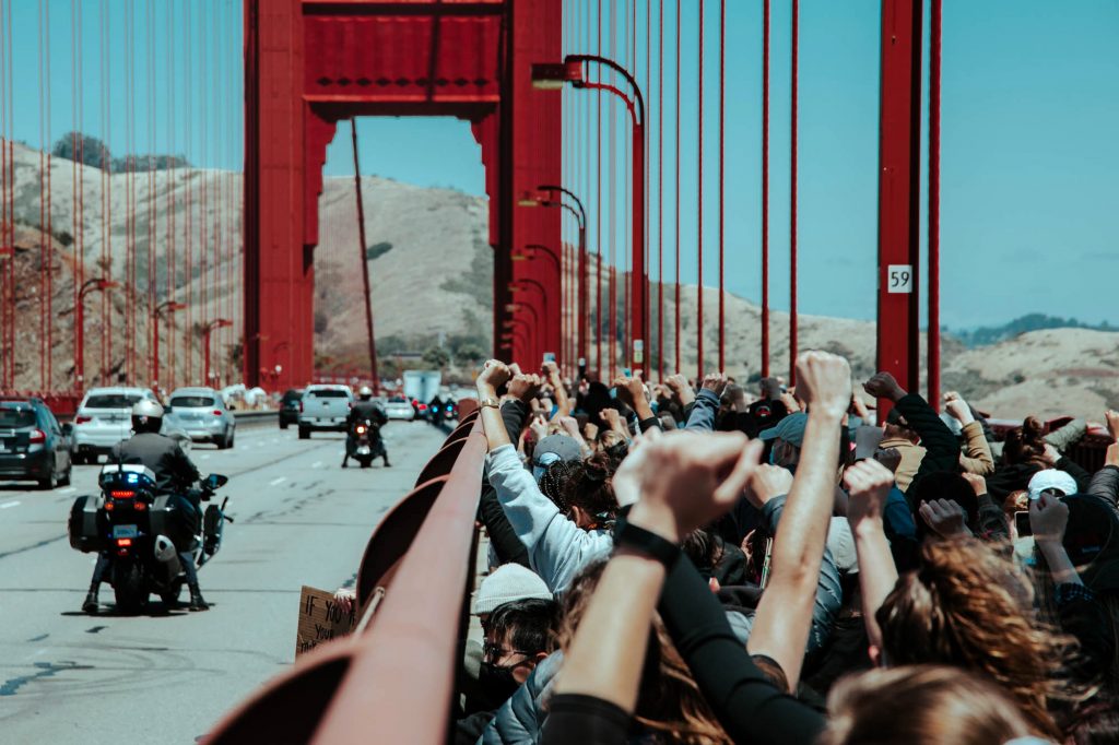 Protesters kneel together and raise their fists on the Golden Gate Bridge.