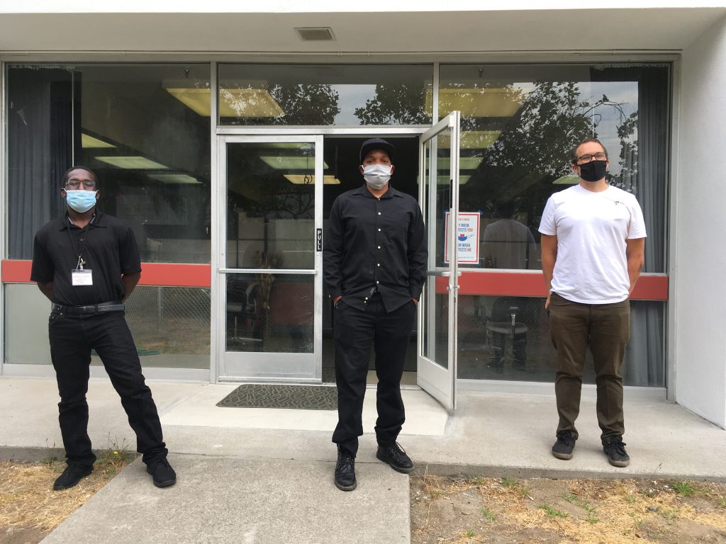 Jermane Gray, Joey Harrison, and Jeremy Pfiefer stand in front of Village of Love, all wearing face masks.