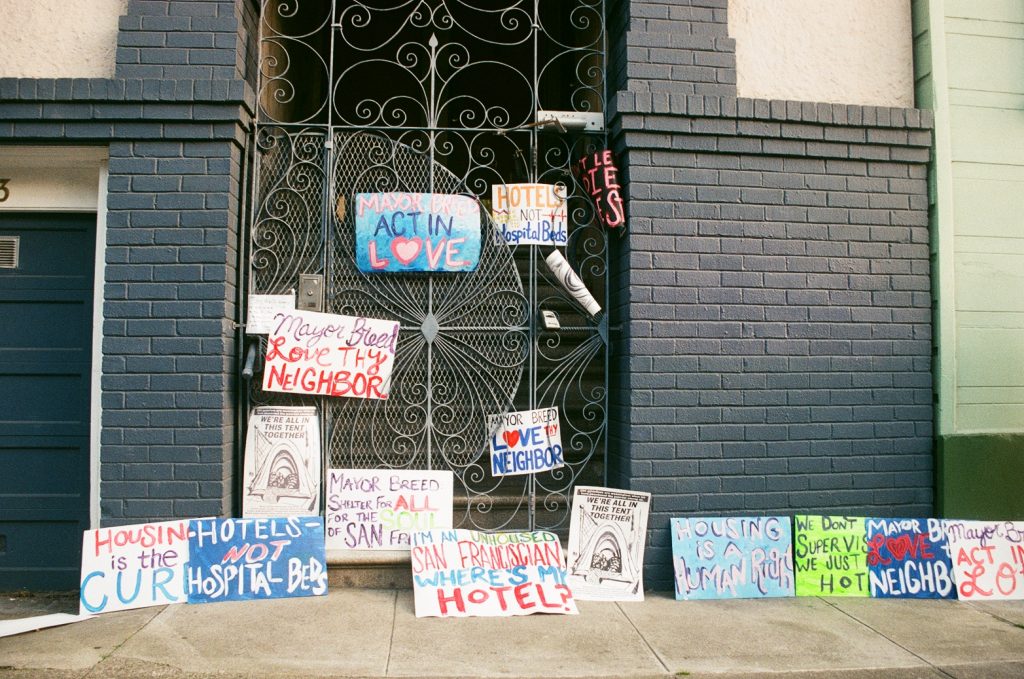 Protest signs adorn SF Mayor London Breed's doorstep during a protest in April, 2020. They say "Act in Love," "Hotels not hospital beds, and "Housing is the cure", amongst other things.