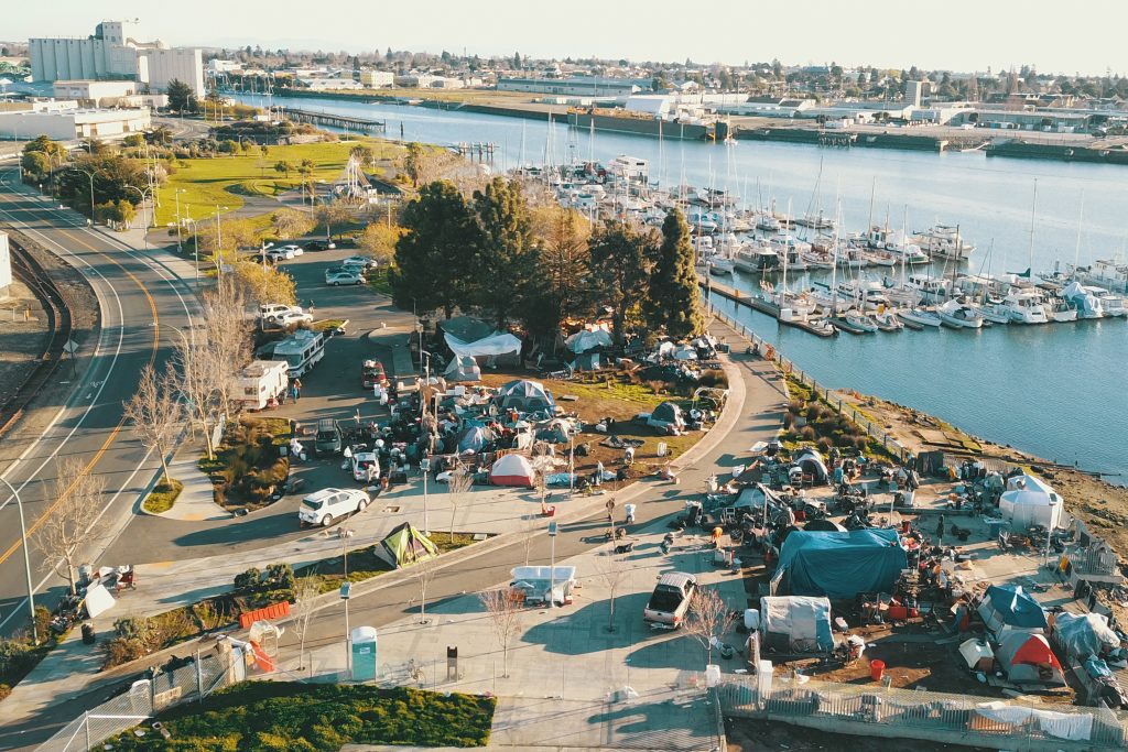An aerial view of the encampment at Union Point Park. Many tents and structures can be seen in the park, which butts up right against the marina, where many boats are parked.