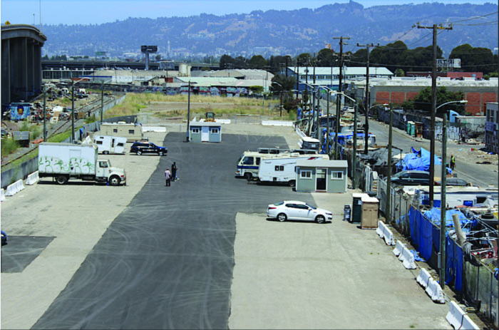 An arial view of a large, nearly-empty parking where five RVs and cars are parked.