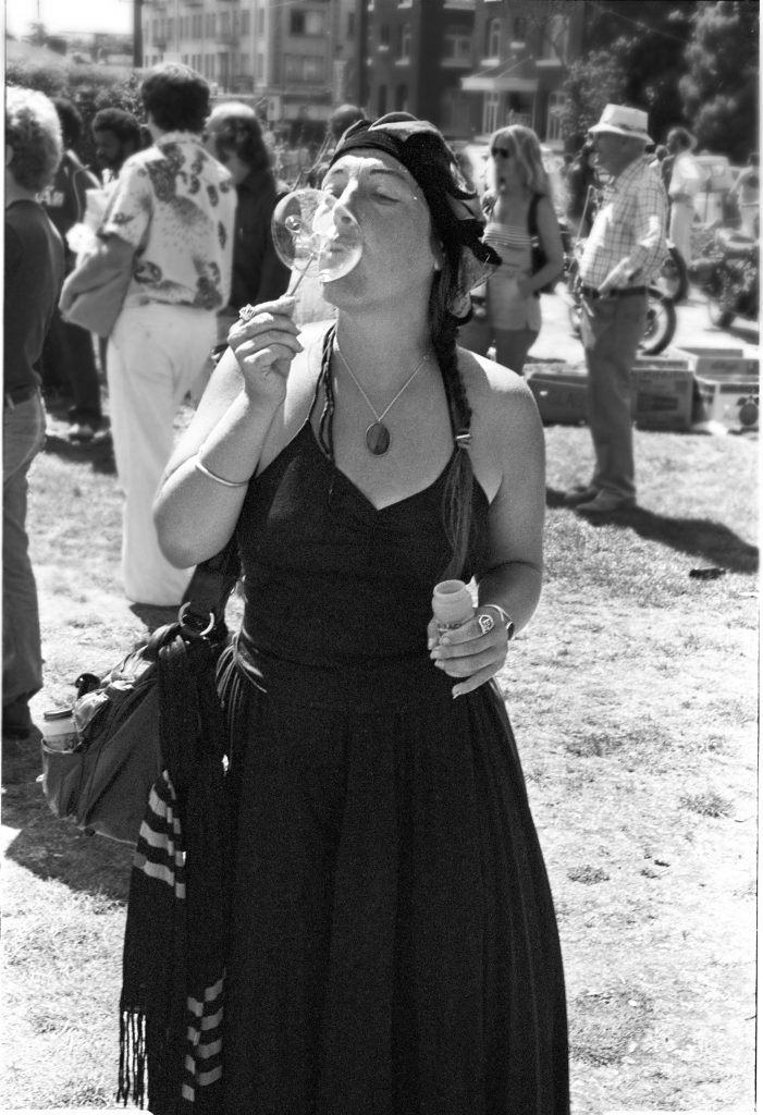 Julia blows a bubble, wearing her classic all black outfit and hat. 