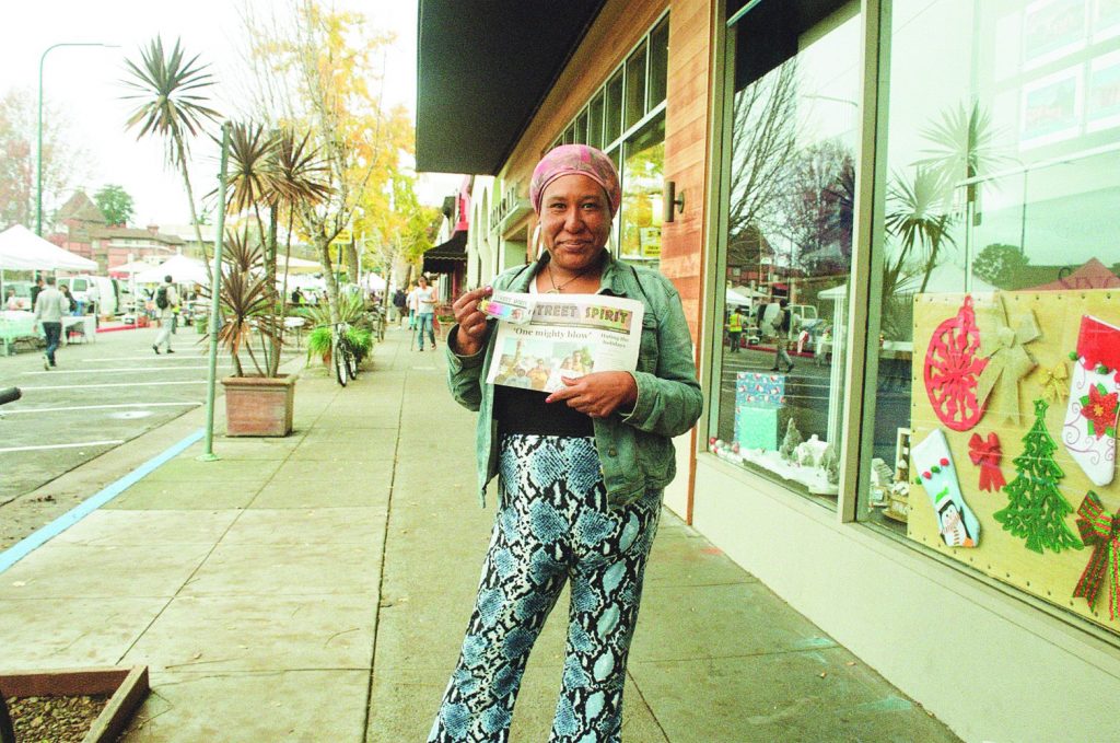 Photo of Melanie Lacy holding a Street Spirit. 