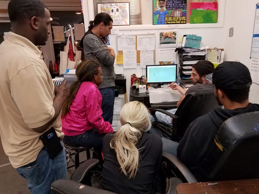 A group of YSA's youth leaders huddle around a computer as they work on a prototype design for the tiny house village.