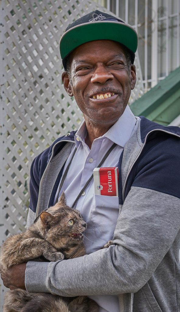 Ken holds his grey cat, Gracie, and smiles.