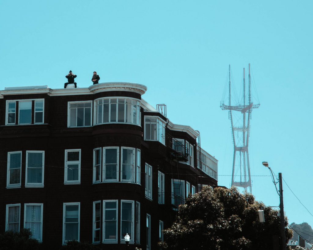 From the roof of a building overlooking Dolores Park, 2 police officers observe the growing protest gathering outside Mission High School.