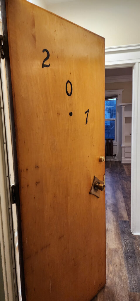 Photograph of a door to an apartment that is partially open to people who want to come inside.