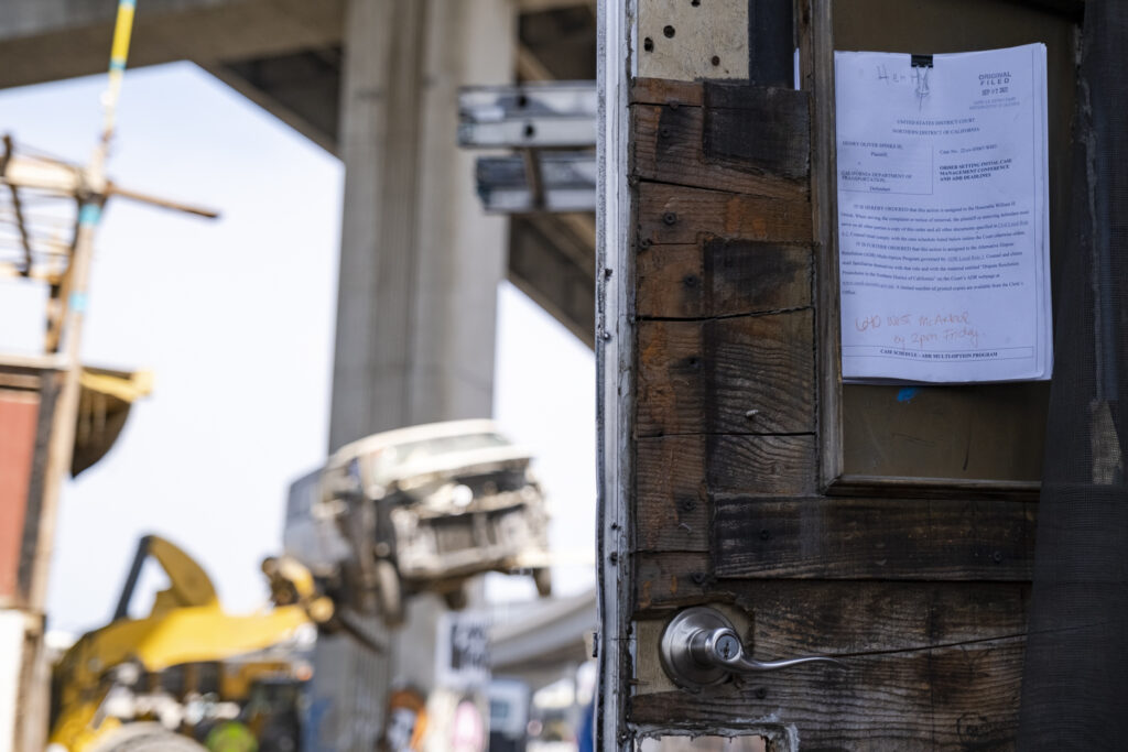 Photo of a wooden door on an rv with a lawsuit posted to it against CALTRANS